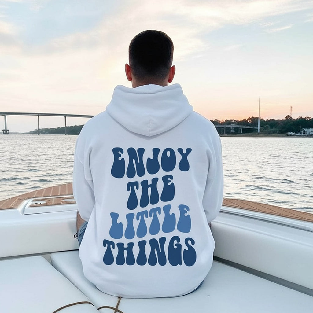 The hoodie worn from behind at dusk, the back print reading Enjoy The Little Things